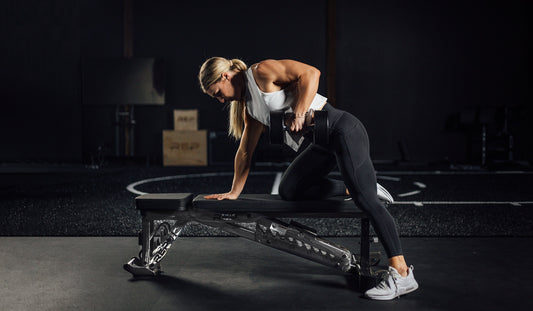 A woman tackles a row while stabilizing herself on an adjustable bench.