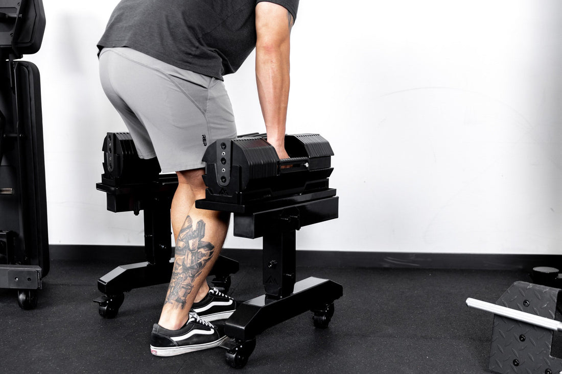 An athlete picks up a pair of REP® x PÉPIN™ FAST Series™ Adjustable Dumbbells.